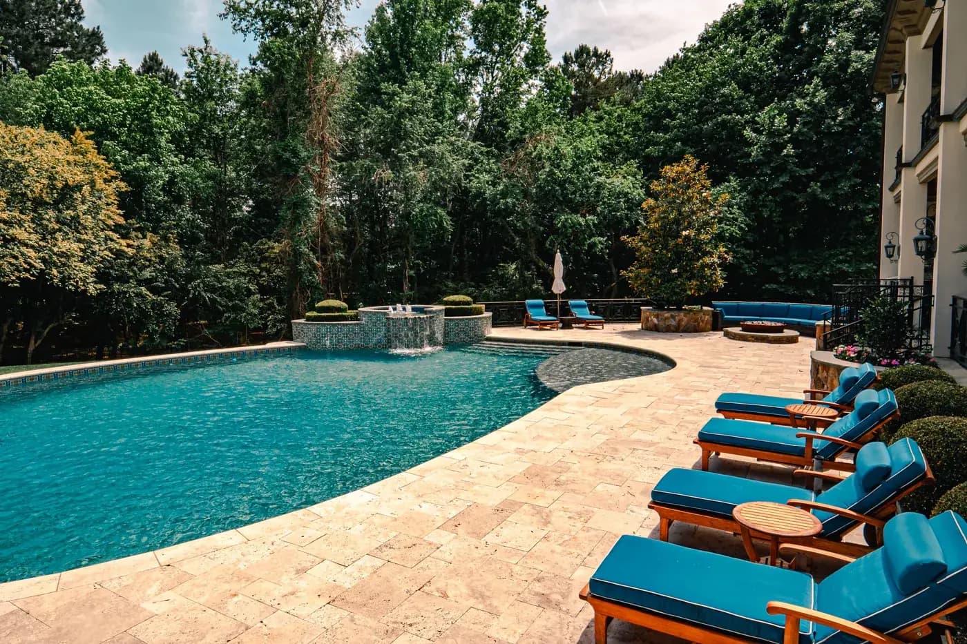 Residential pool with stone decking and blue lounge chairs
