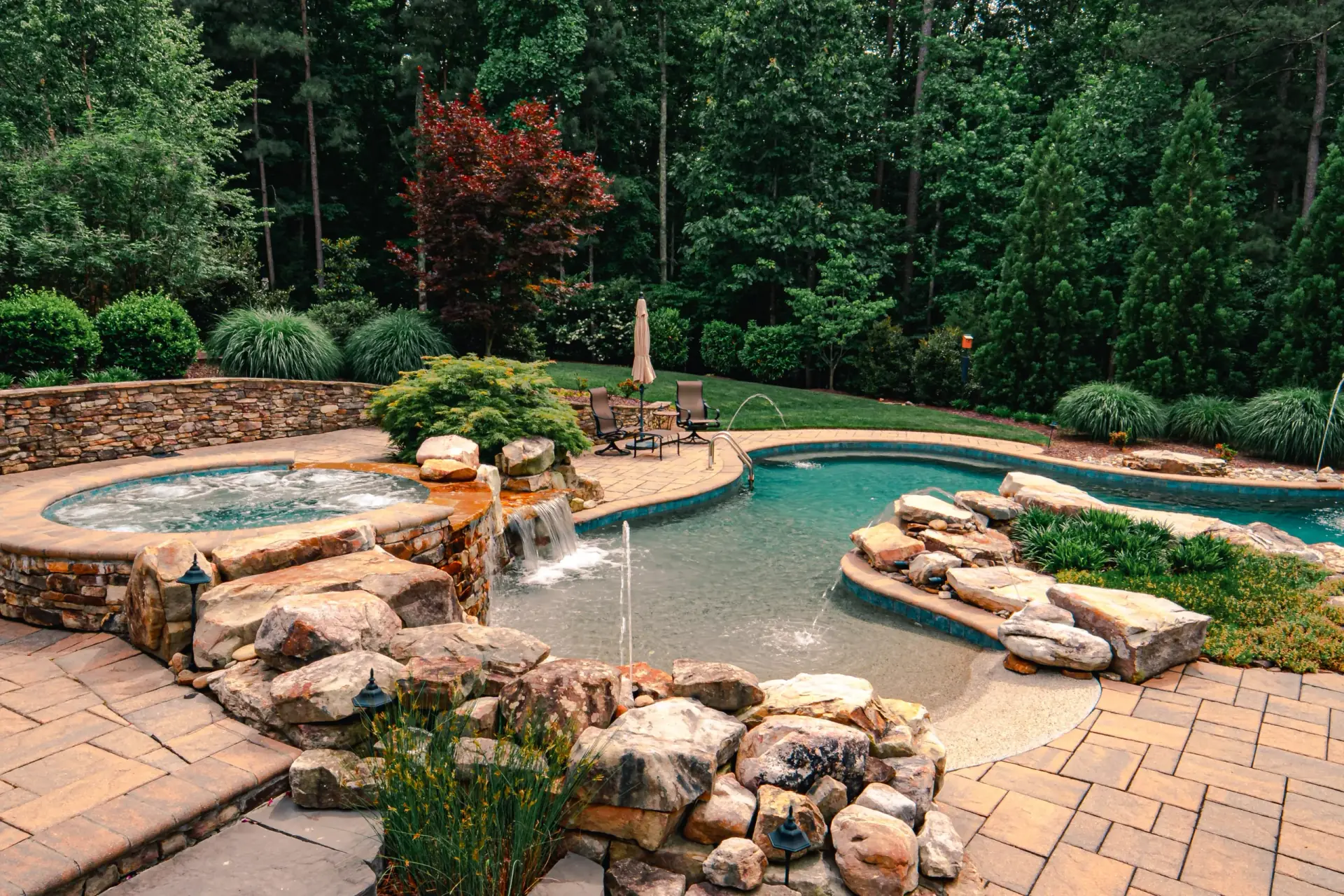 Inground swimming pool and raised spa with landscaped stone decking